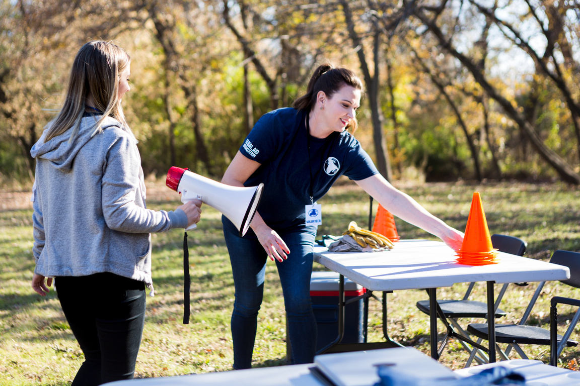 Event coordinator sets up traffic cones while helper brings bullhorn